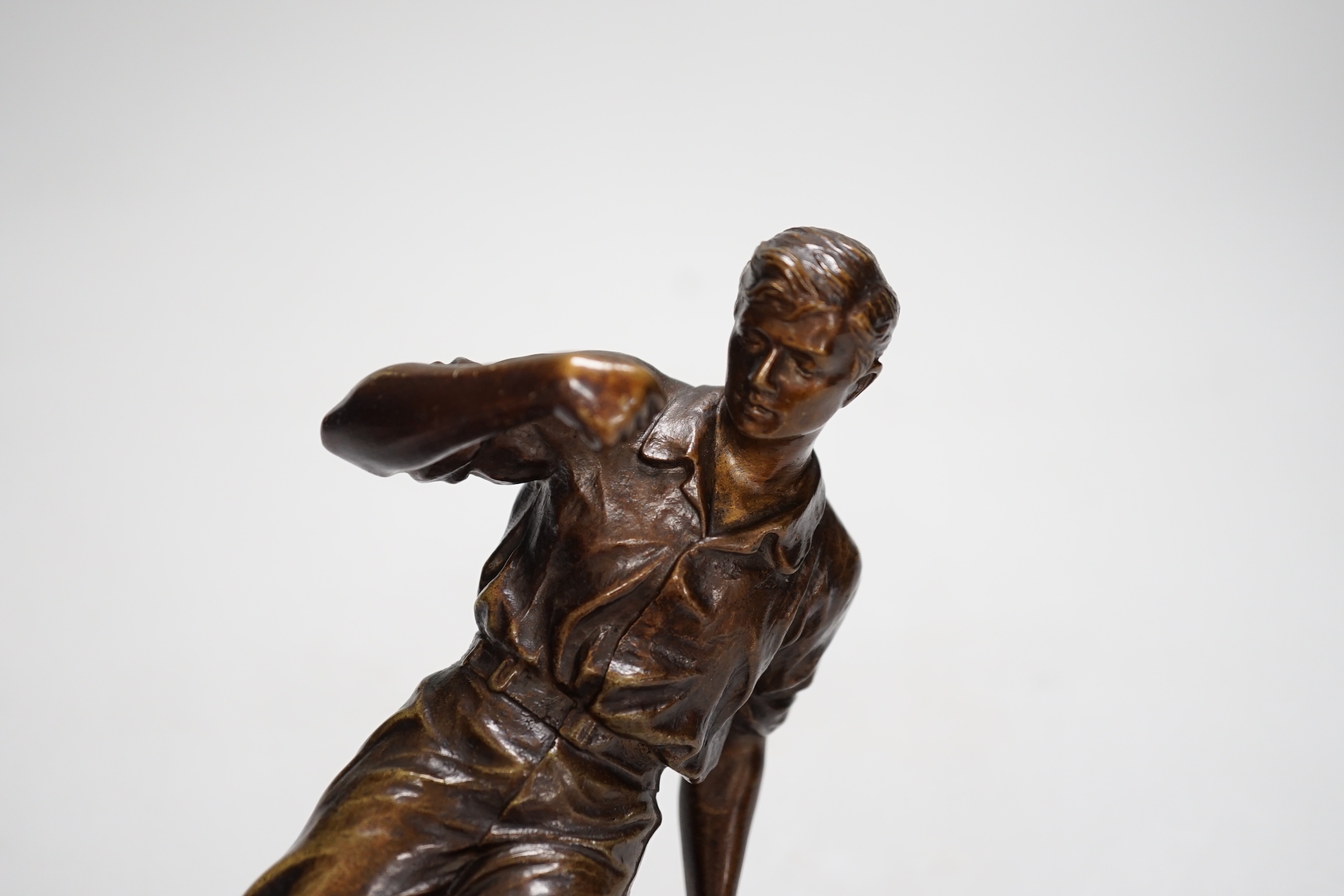 A pre-war bronze figure of a footballer, raised on a circular ebonies wood base, 23cm high